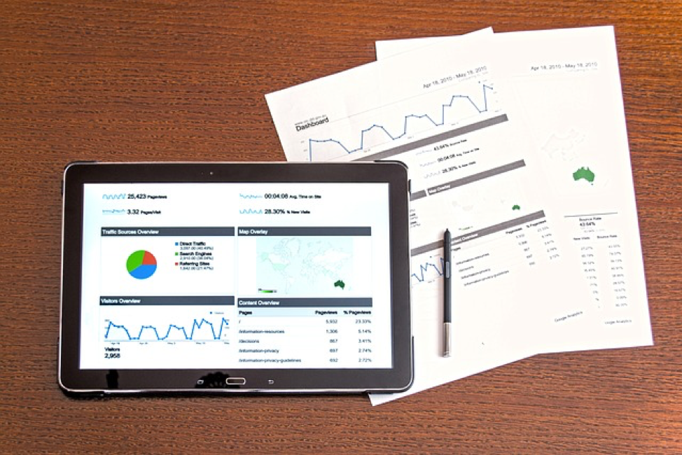 A tablet with graphs adjacent to papers displaying data. A pencil sits atop the papers. 